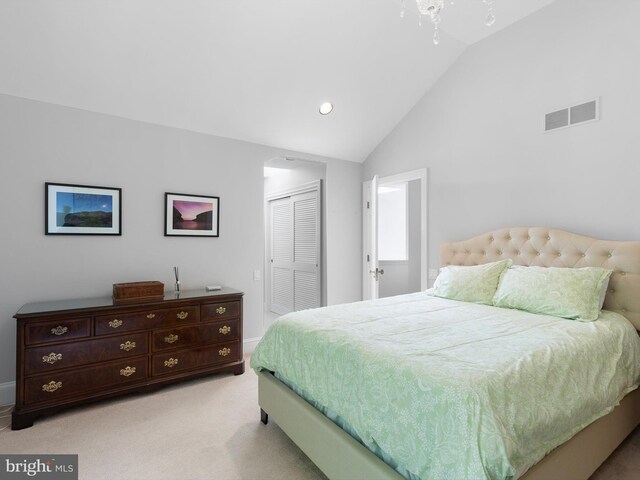 bedroom featuring a closet, visible vents, baseboards, light colored carpet, and vaulted ceiling