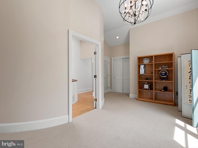 interior space with baseboards, high vaulted ceiling, a closet, a chandelier, and carpet flooring
