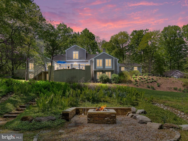 back of property at dusk featuring a fire pit