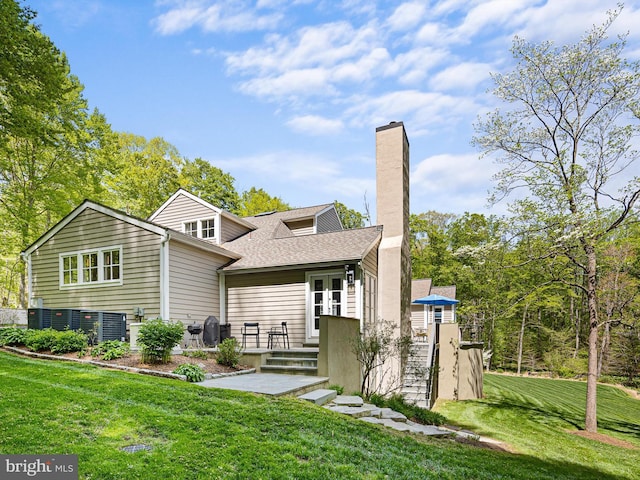 back of property with a yard, a chimney, and roof with shingles
