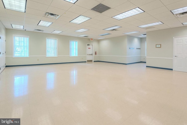 empty room featuring baseboards, a drop ceiling, and visible vents