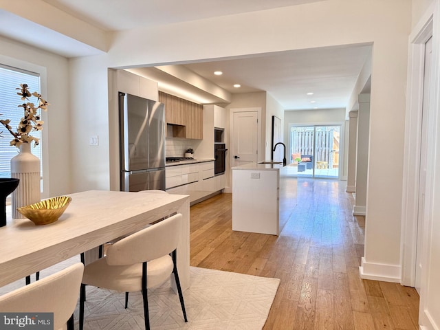 kitchen featuring appliances with stainless steel finishes, a sink, light wood finished floors, and modern cabinets