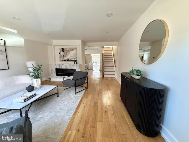 living room with stairs, baseboards, and light wood-style flooring