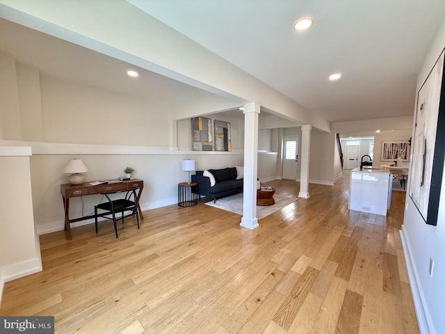 interior space with recessed lighting, baseboards, light wood finished floors, and ornate columns