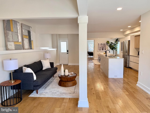 living area featuring recessed lighting, light wood-style floors, baseboards, and decorative columns