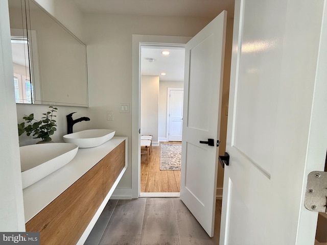 bathroom featuring recessed lighting, a sink, wood finished floors, and double vanity
