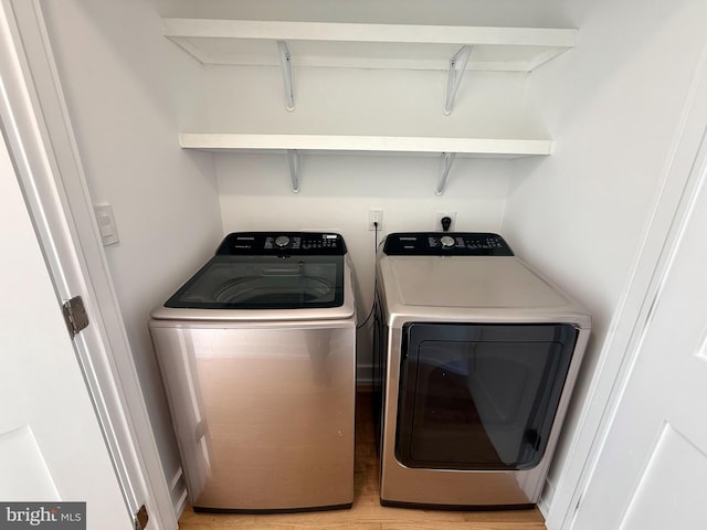 washroom featuring laundry area, washing machine and dryer, and light wood-style floors