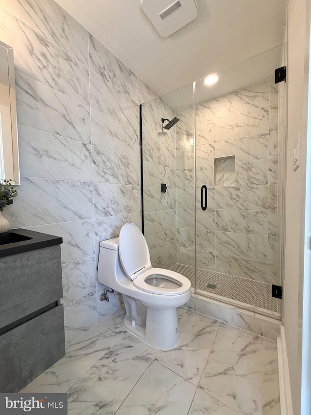 full bath with vanity, marble finish floor, toilet, tile walls, and a shower stall