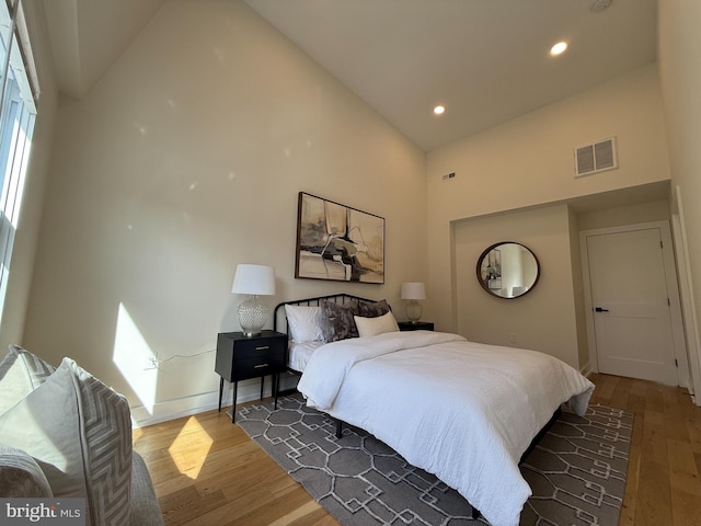 bedroom featuring visible vents, wood finished floors, high vaulted ceiling, baseboards, and recessed lighting