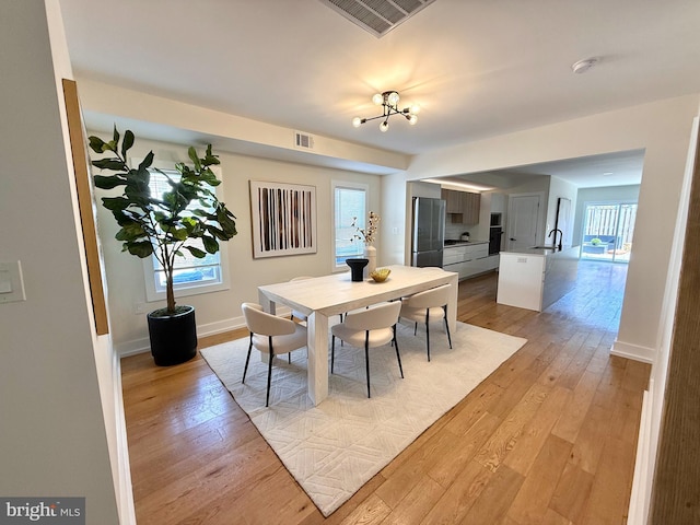 dining area featuring visible vents, light wood-style floors, and baseboards