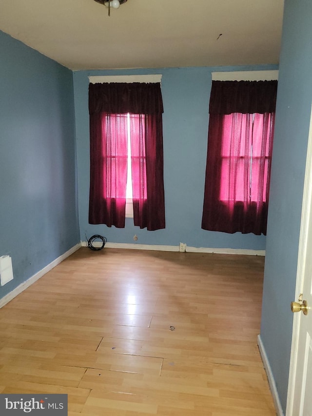unfurnished room with baseboards and wood finished floors
