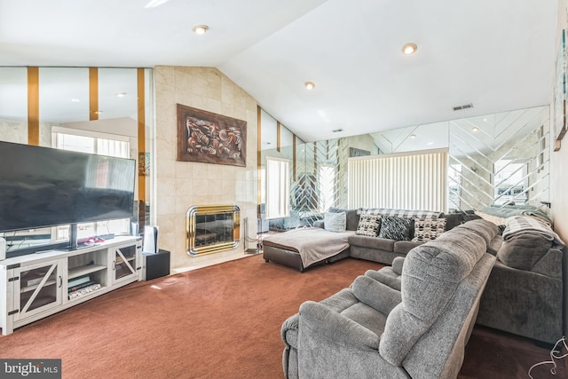 carpeted living room with a tiled fireplace, vaulted ceiling, and visible vents