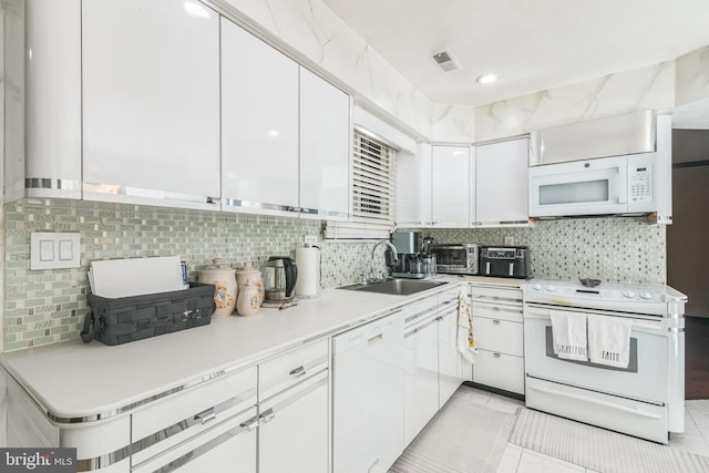 kitchen featuring white appliances, backsplash, white cabinets, and a sink