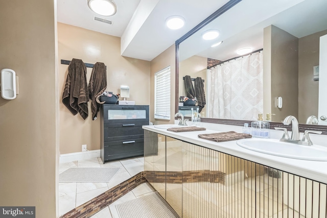 bathroom featuring double vanity, a sink, baseboards, and visible vents