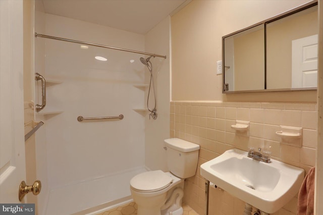full bathroom featuring a sink, tile patterned flooring, toilet, tile walls, and a shower