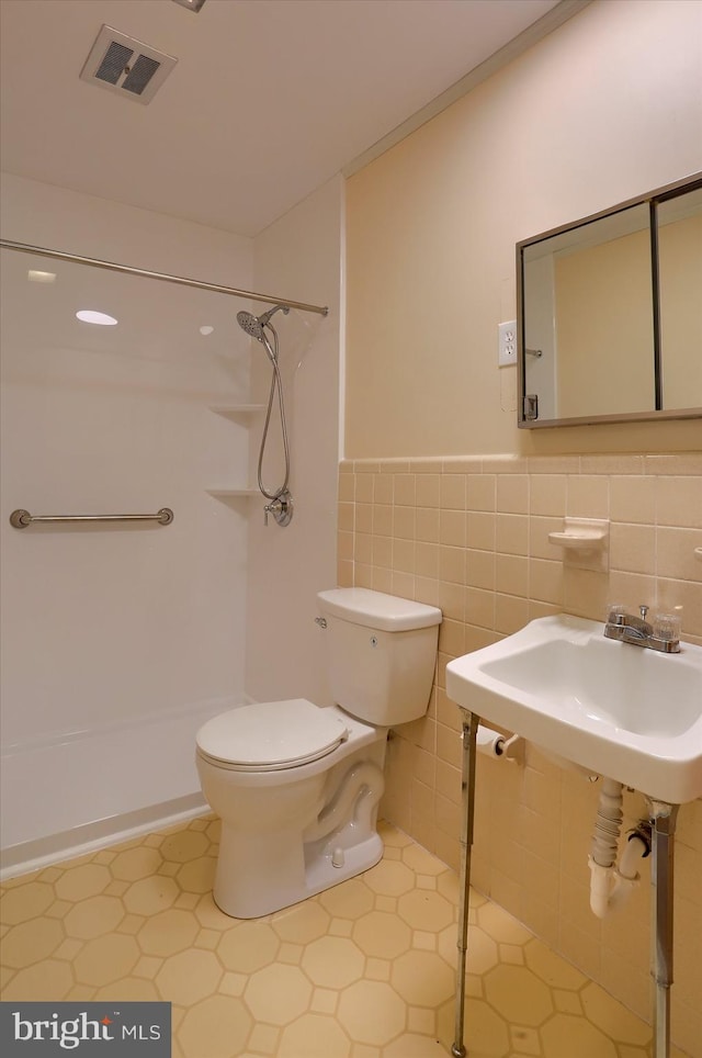 full bathroom featuring walk in shower, a sink, toilet, tile walls, and visible vents
