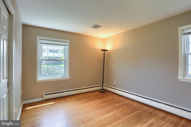 unfurnished room with light wood-type flooring, baseboards, baseboard heating, and visible vents