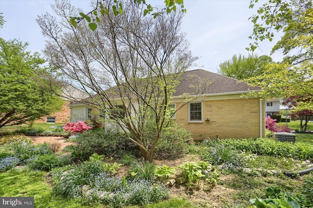 view of home's exterior with brick siding and roof with shingles
