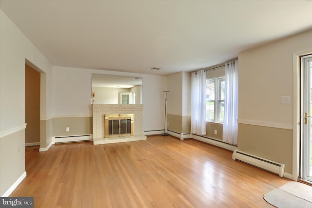 unfurnished living room featuring light wood-style floors, a baseboard radiator, a baseboard heating unit, and a brick fireplace