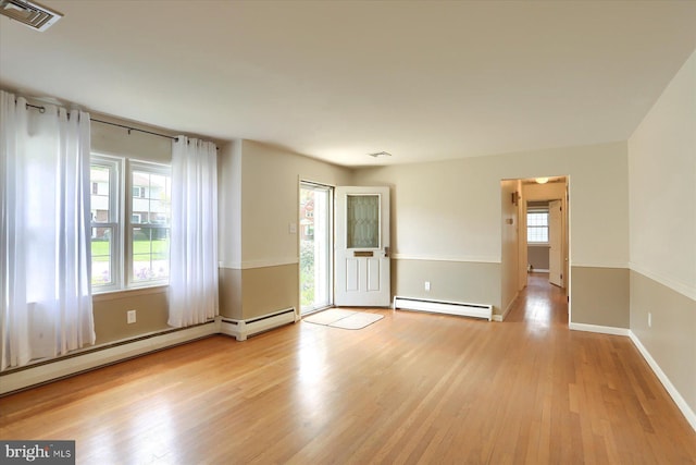 spare room featuring baseboards, baseboard heating, wood finished floors, and visible vents