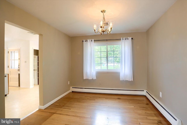 spare room featuring an inviting chandelier, baseboard heating, baseboards, wood finished floors, and a baseboard radiator