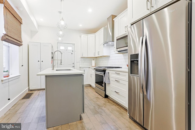 2325 W Thompson St, Philadelphia, PA 19121 - kitchen with wall chimney range hood, appliances with stainless steel finishes, a sink, a kitchen island with sink, and light countertops