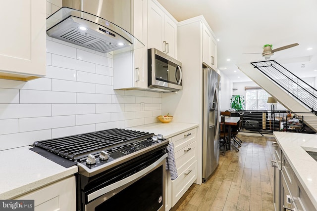 2325 W Thompson St, Philadelphia, PA 19121 - kitchen featuring light wood-style floors, stainless steel appliances, extractor fan, and white cabinetry