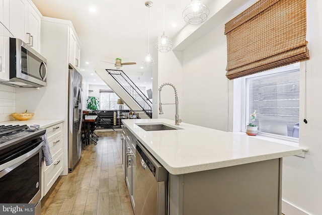 2325 W Thompson St, Philadelphia, PA 19121 - kitchen featuring white cabinets, appliances with stainless steel finishes, a sink, light wood-style floors, and an island with sink