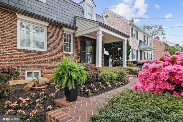view of side of property featuring mansard roof and brick siding