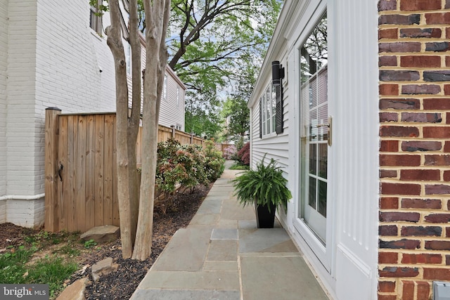 view of property exterior with brick siding and fence