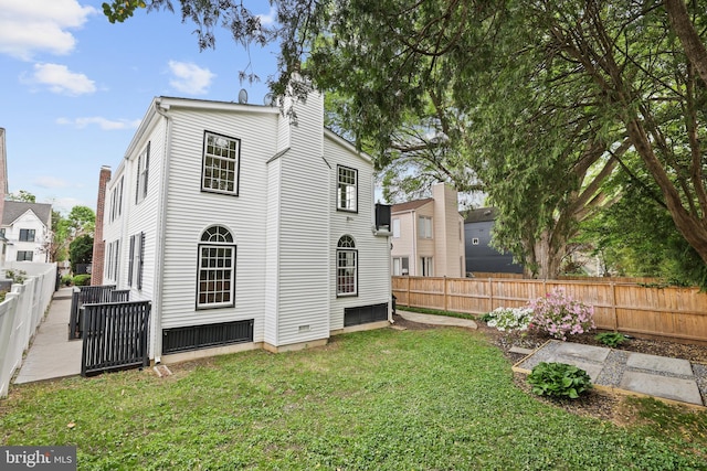 rear view of property with a lawn, a chimney, and a fenced backyard