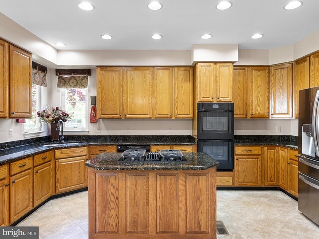 345 Jessica Dr, Middletown, DE 19709 - kitchen featuring brown cabinetry, a center island, a sink, dark stone countertops, and black appliances
