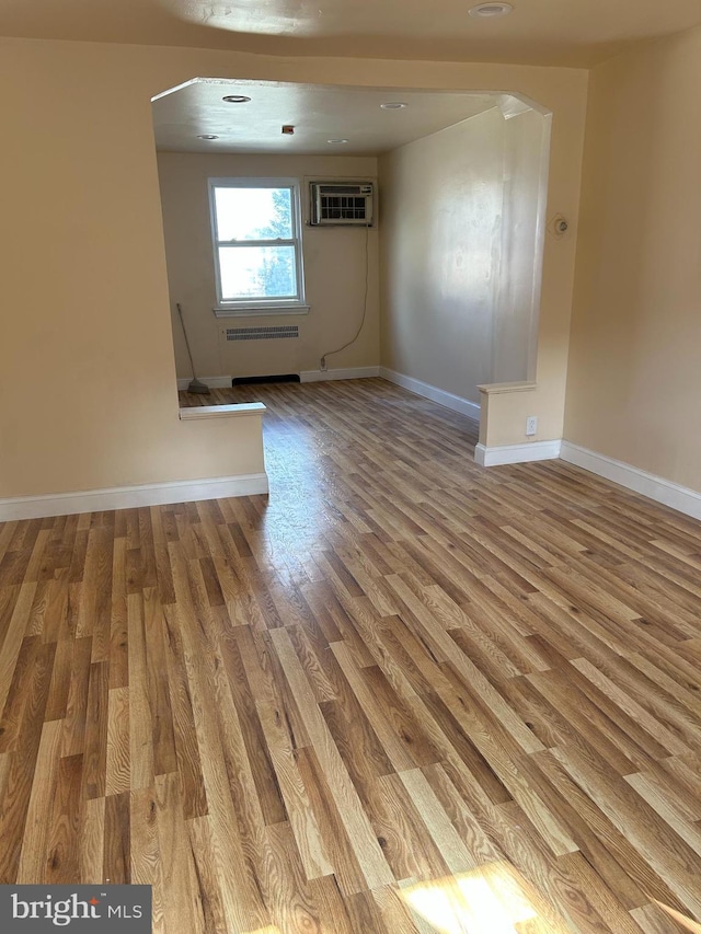 577 Snowden Rd, Upper Darby, PA 19082 - unfurnished room featuring arched walkways, baseboards, a wall unit AC, and wood finished floors