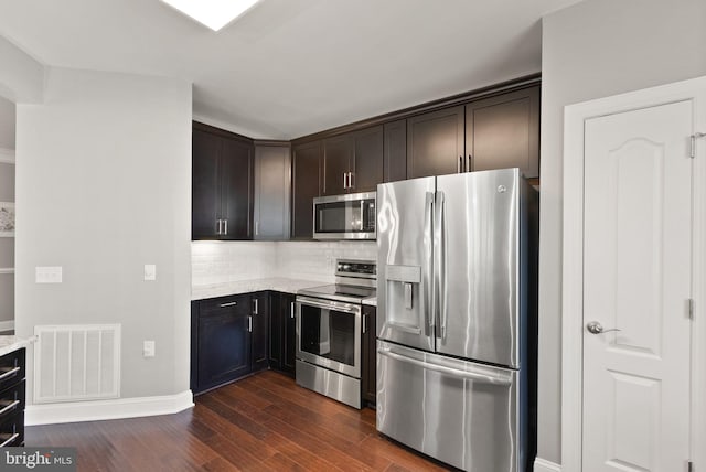 kitchen featuring visible vents, decorative backsplash, dark wood-style flooring, light stone countertops, and stainless steel appliances