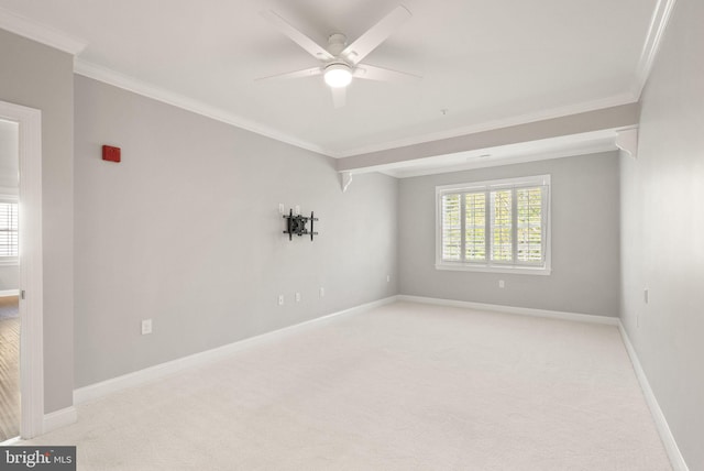 empty room with carpet floors, ornamental molding, baseboards, and a ceiling fan