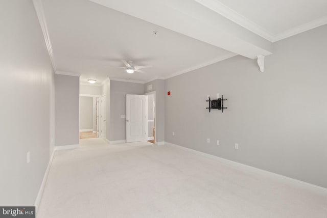 spare room featuring crown molding, baseboards, ceiling fan, and carpet