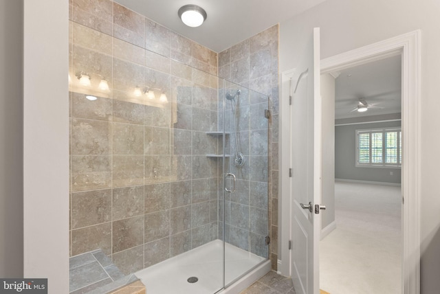 full bath featuring ceiling fan, a shower stall, and baseboards