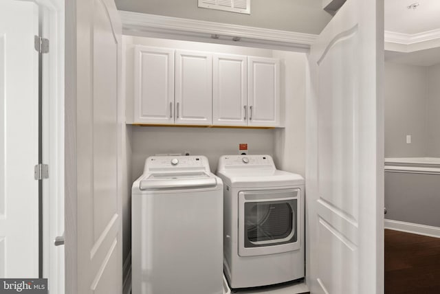 clothes washing area with visible vents, ornamental molding, washing machine and dryer, baseboards, and cabinet space