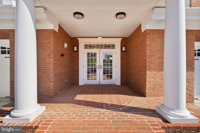 view of exterior entry featuring brick siding and french doors