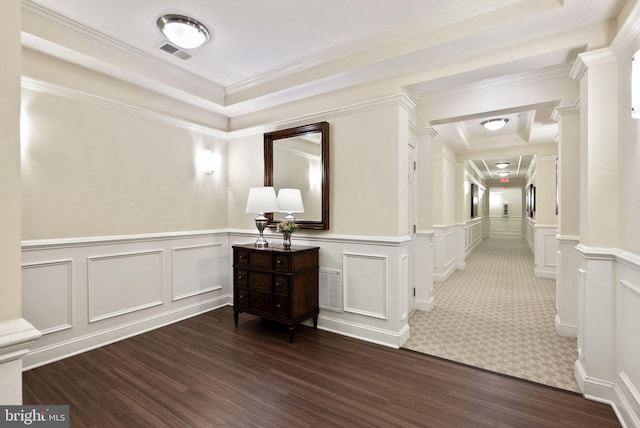 corridor featuring visible vents, crown molding, a decorative wall, and wood finished floors