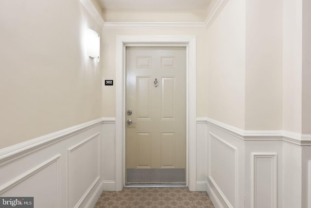 doorway to outside featuring wainscoting and a decorative wall