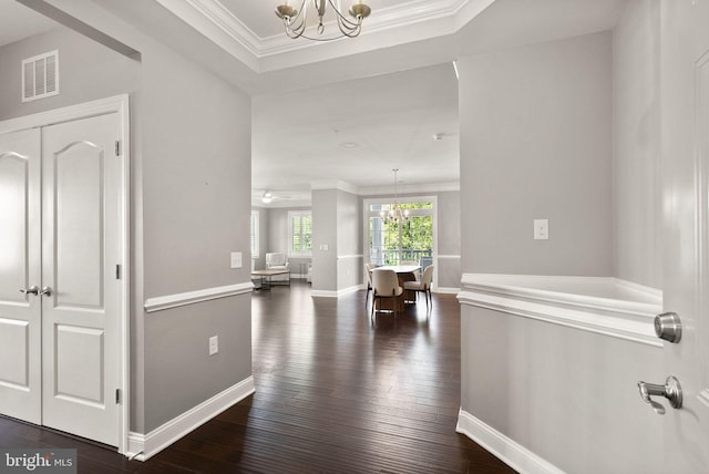 hall featuring crown molding, an inviting chandelier, visible vents, and dark wood-type flooring