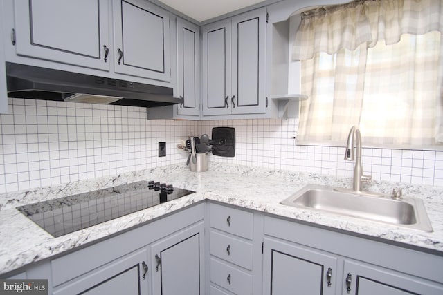 kitchen featuring decorative backsplash, black electric cooktop, under cabinet range hood, a sink, and gray cabinetry