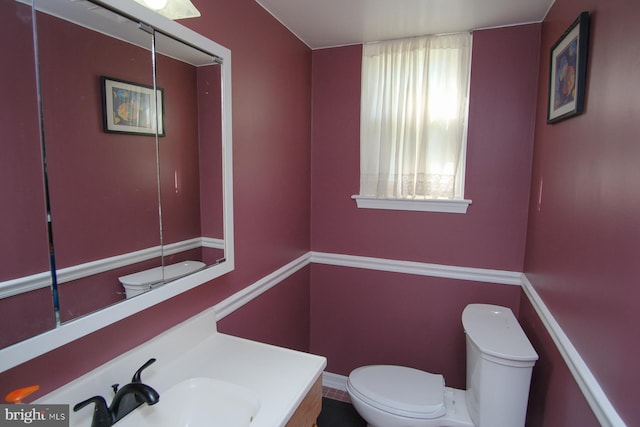 half bathroom featuring vanity and toilet