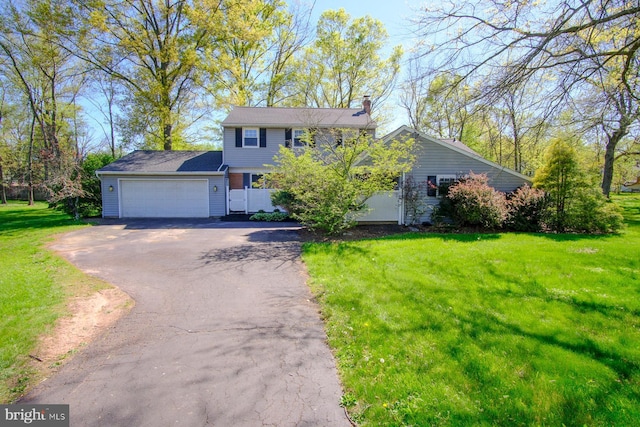 view of front of property featuring an attached garage, a chimney, a front lawn, and aphalt driveway