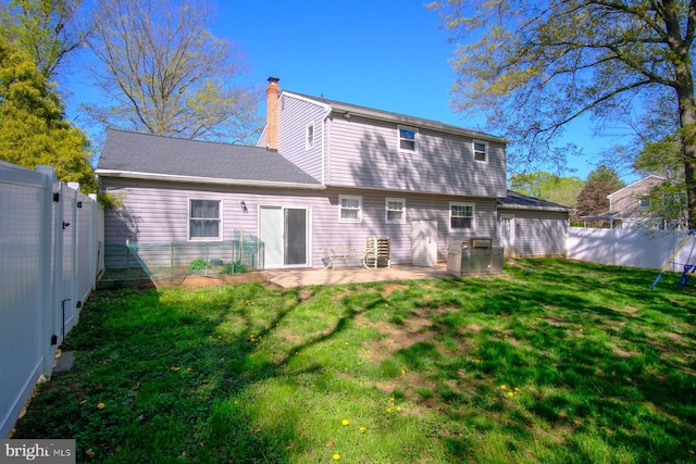 back of house featuring a fenced backyard, a patio, a chimney, and a yard