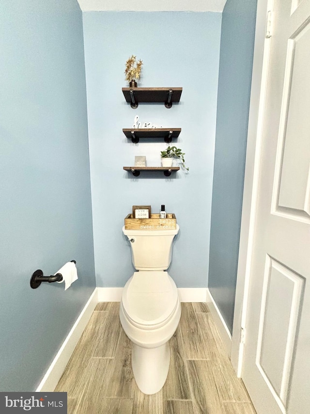 bathroom featuring wood finish floors, baseboards, and toilet