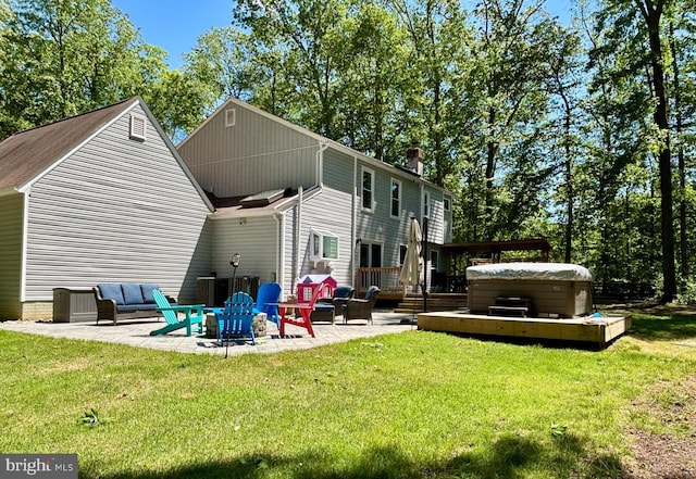 rear view of property featuring a hot tub, a patio, a yard, and a chimney