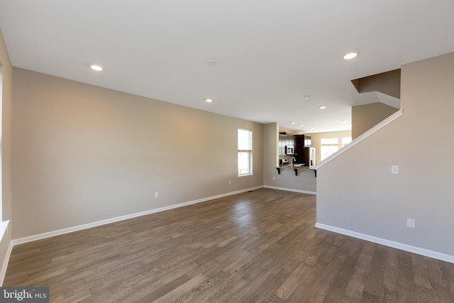 unfurnished living room featuring recessed lighting, baseboards, and dark wood-type flooring