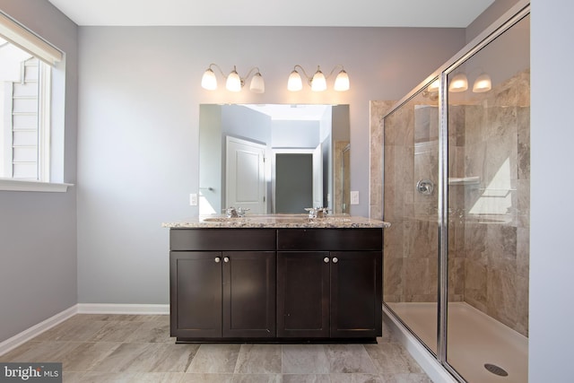 full bathroom with double vanity, baseboards, a shower stall, and a sink